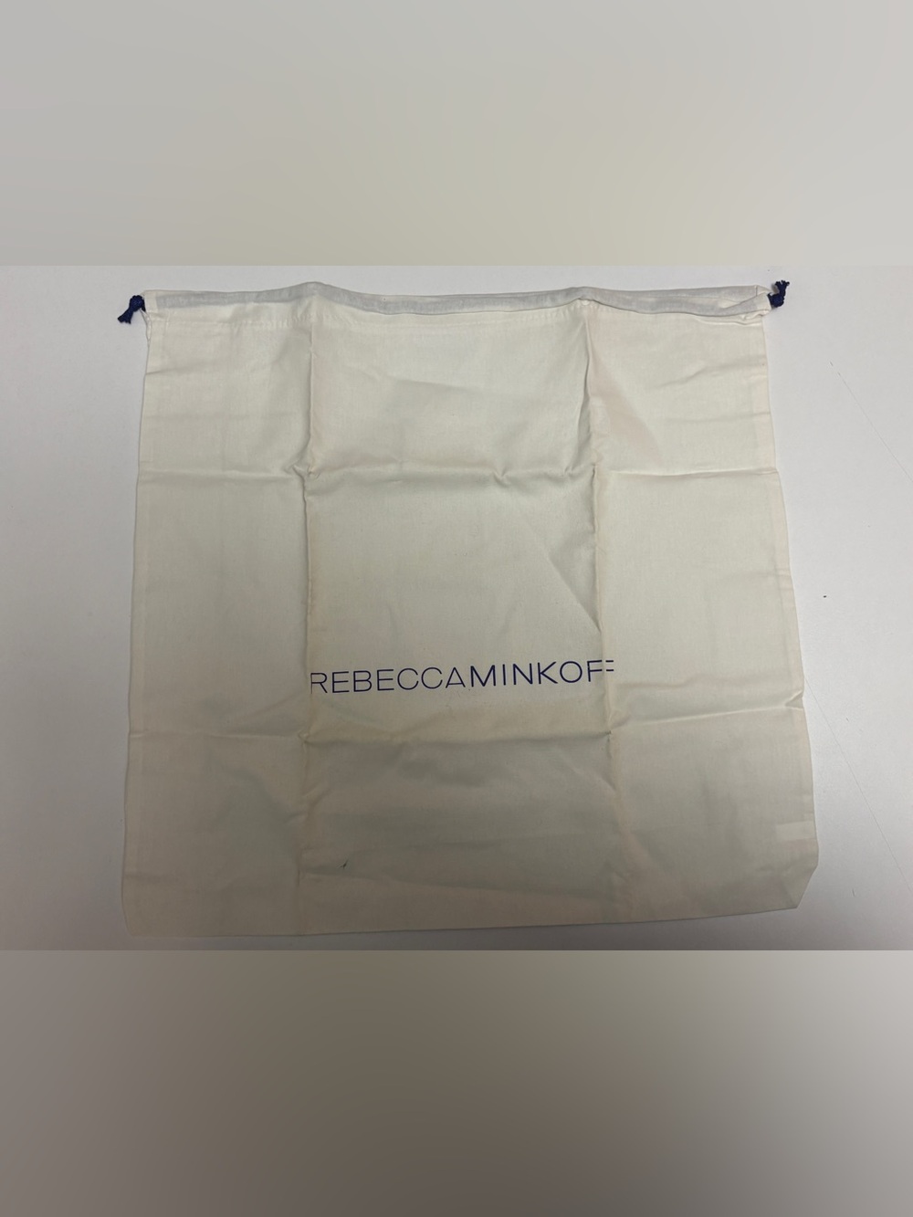 Rebecca Minkoff cream drawstring storage bag with navy logo